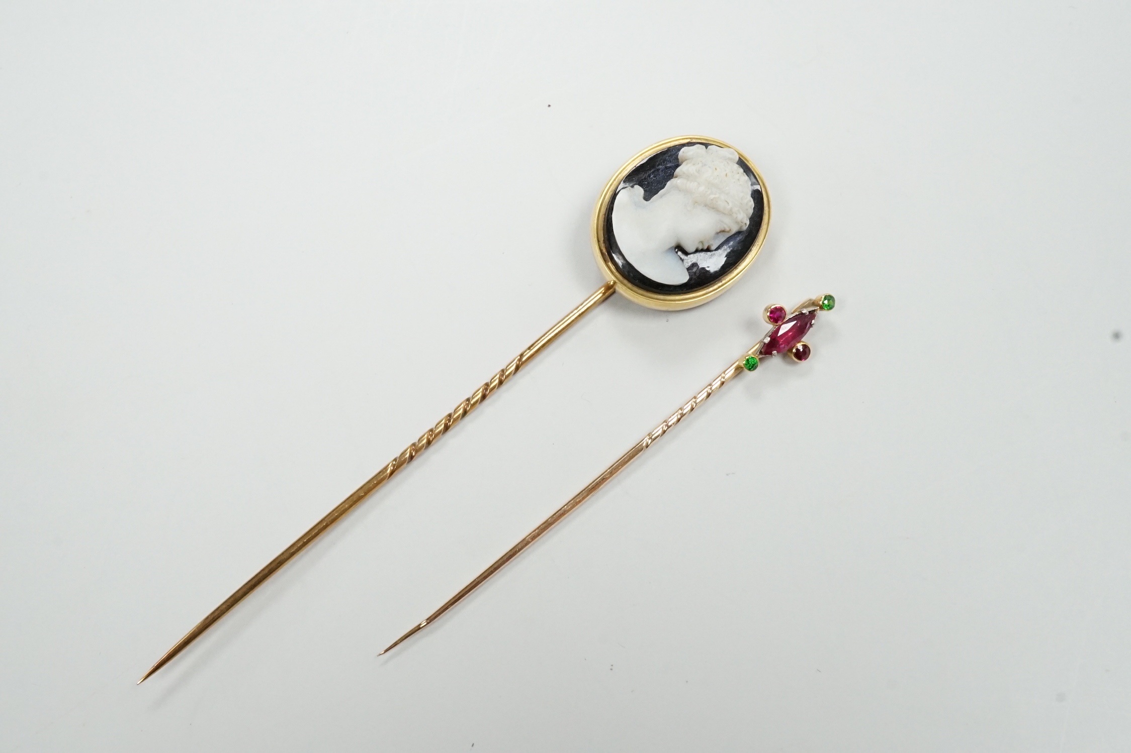 A yellow metal and sardonyx cameo stick pin, 91mm and one other gem set stick pin.